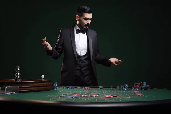 Um homem concentrado em seu laptop com estatísticas ao vivo ao fundo, destacando os recursos dedicados de esportes e jogos do app móvel 44FF.